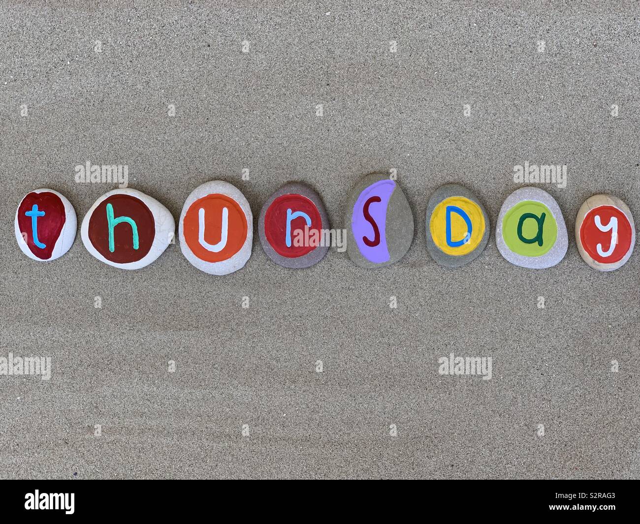 Donnerstag, vierter Tag der Woche besteht aus mehreren farbigen Kiesel Briefe über braunen Sand - Smartphone-aufgenommenes Stockfoto