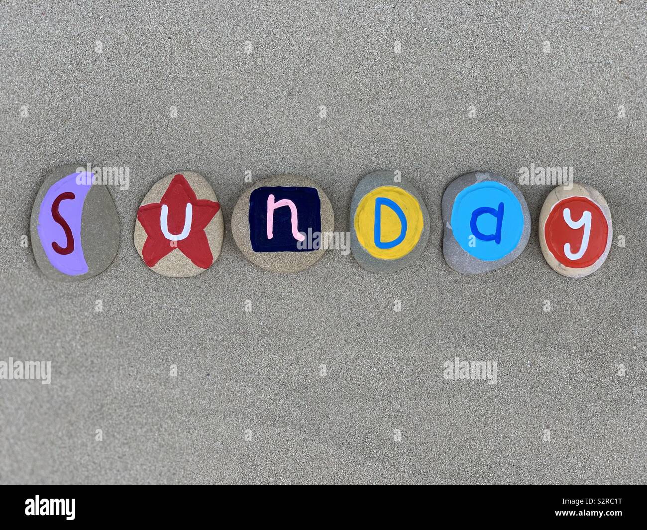 Sonntag, den siebten Tag der Woche besteht aus farbigen Steinen über braunen Sand - Smartphone-aufgenommenes Stockfoto