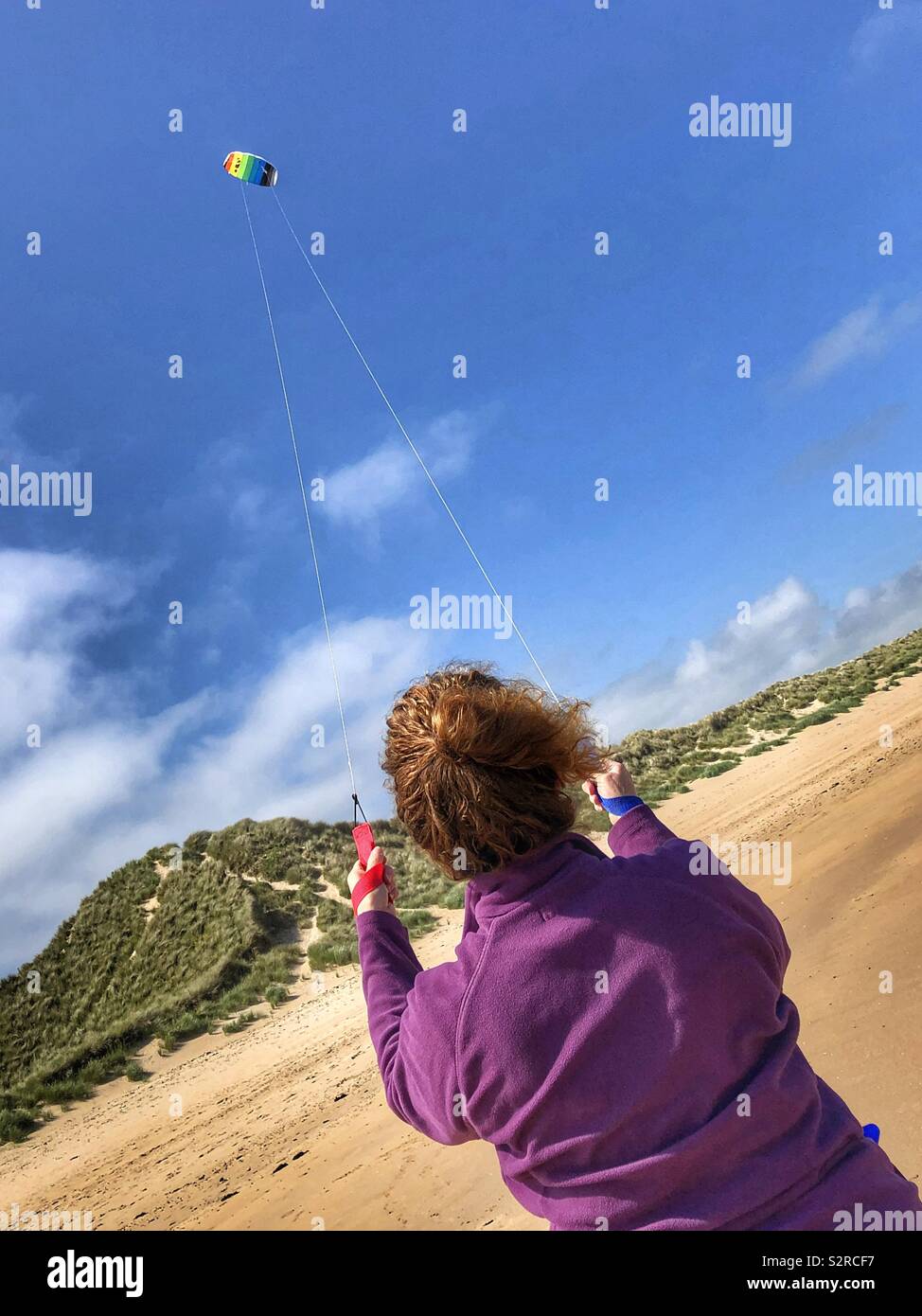 Eine Frau flying a Kite auf Alnmouth Strand Stockfoto