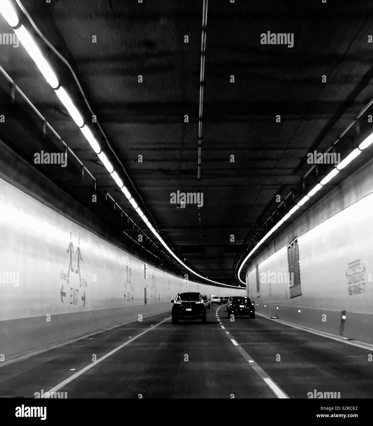 Auto bewegt sich in einem Tunnel. Zwei Autos fahren durch den Tunnel. Schwarz und Weiß. Stockfoto