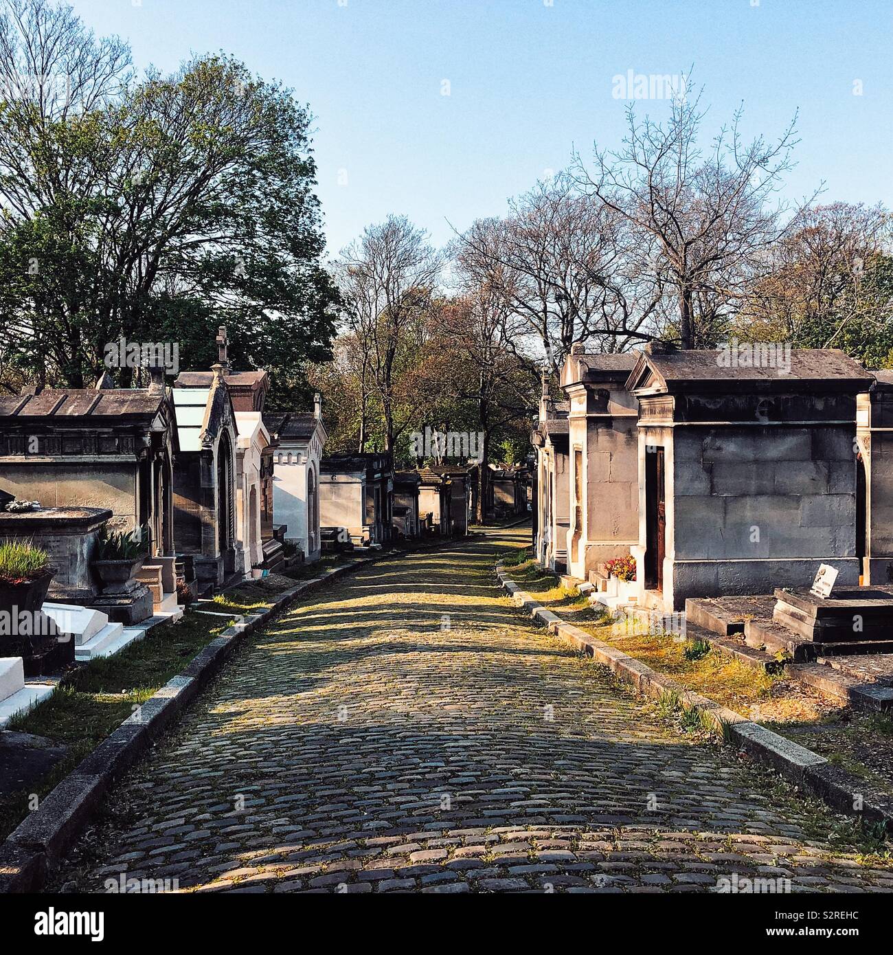 Sonne scheint auf der Straße mit Kopfsteinpflaster und Grabsteine auf dem Friedhof Père Lachaise öffentlichen und nicht konfessionsgebundene Friedhof in Paris. Stockfoto