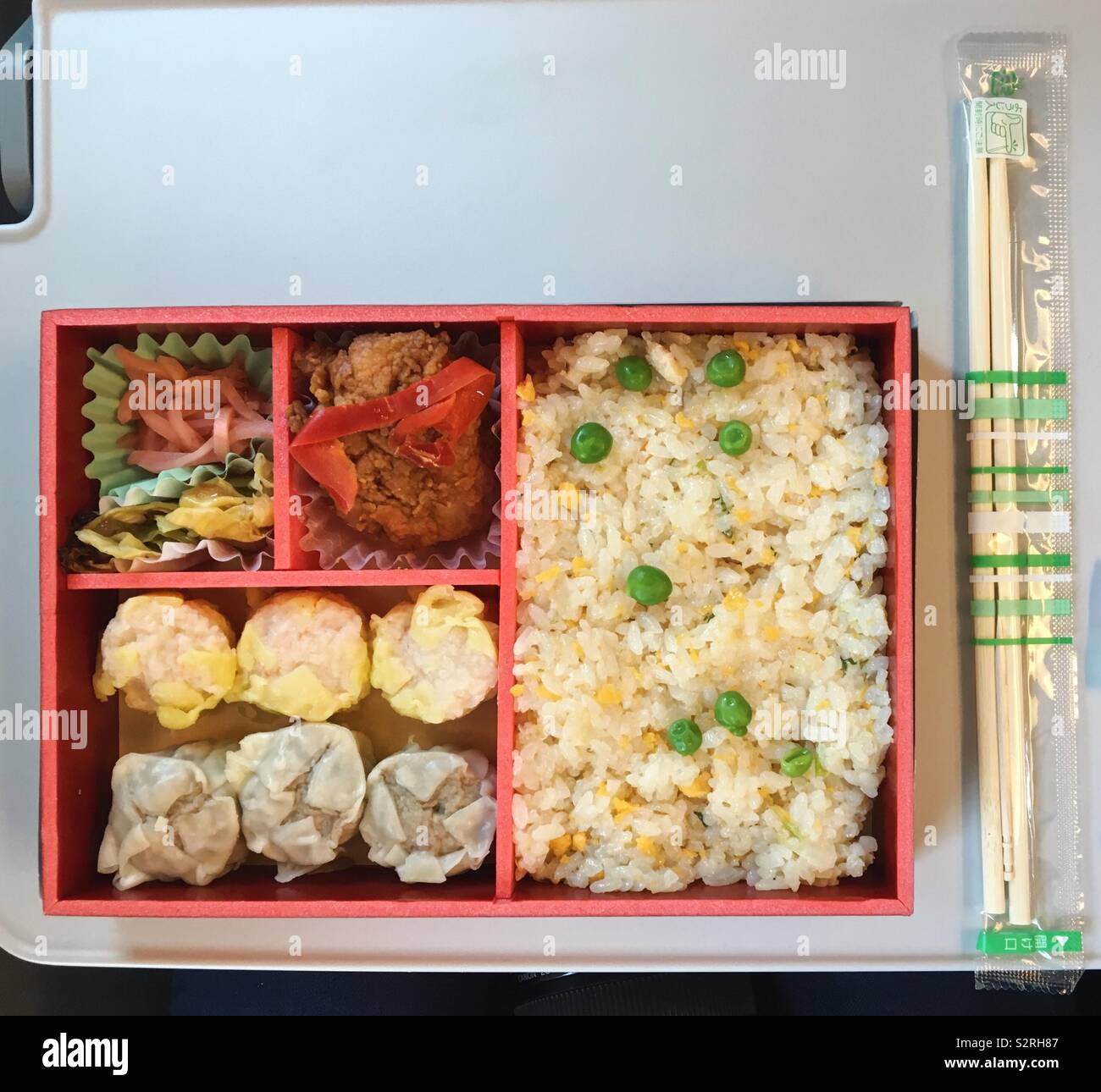 Bento Box auf einer Zugfahrt, mit Essiggurken, gebratenes Huhn, Knödel und gebratener Reis mit Erbsen Stockfoto