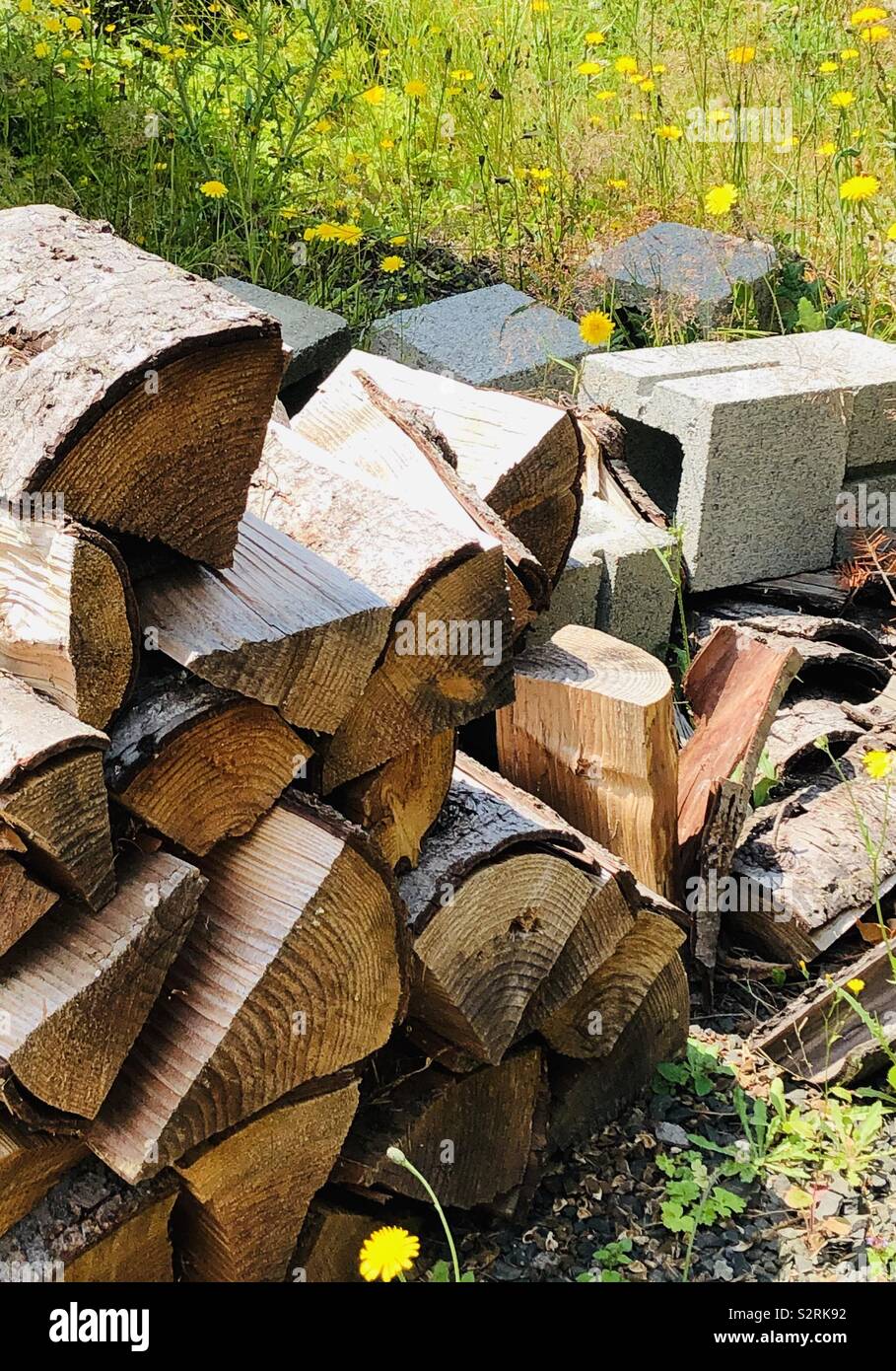 Stapel von Split Holz, Hohlblocksteine, und Unkraut. Stockfoto