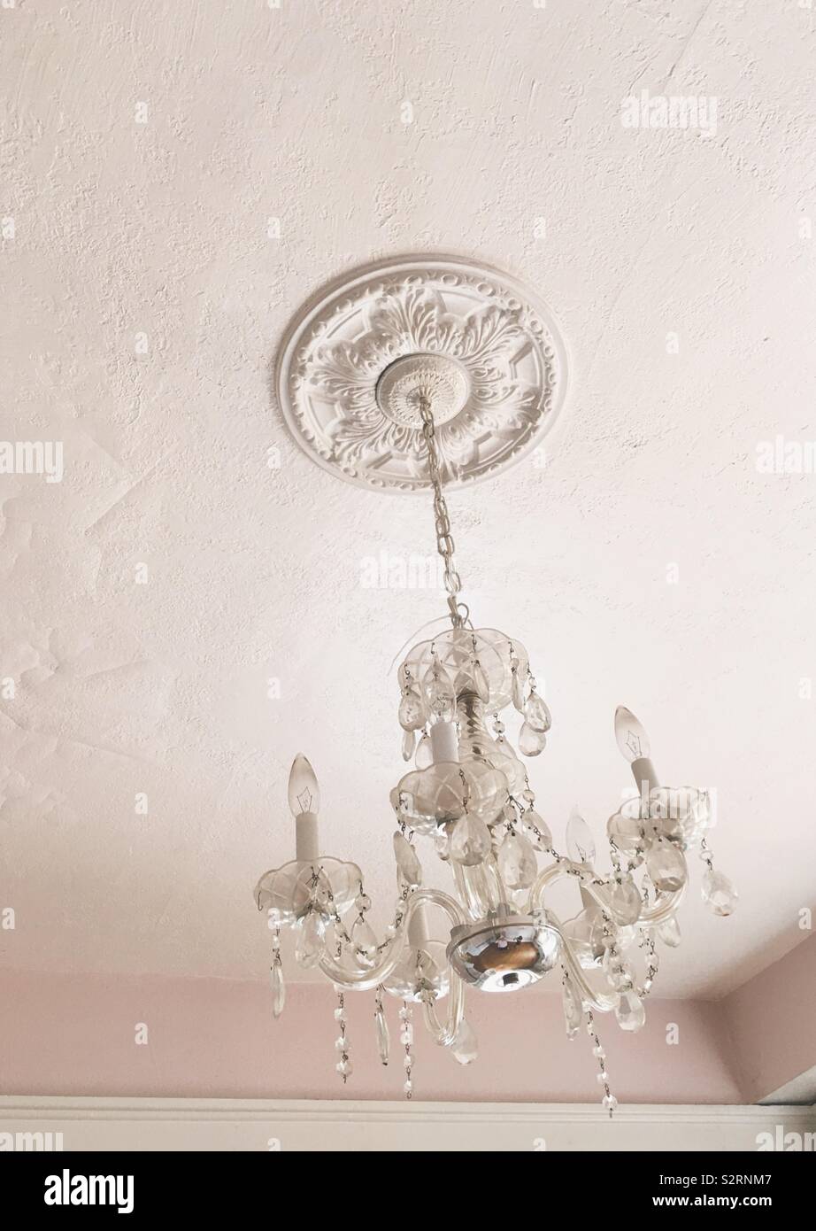 Reich verzierte, Vintage kristall Kronleuchter hängen von einem hellen rosa bemalten Decke. Interieur Home Decor Foto. Stockfoto