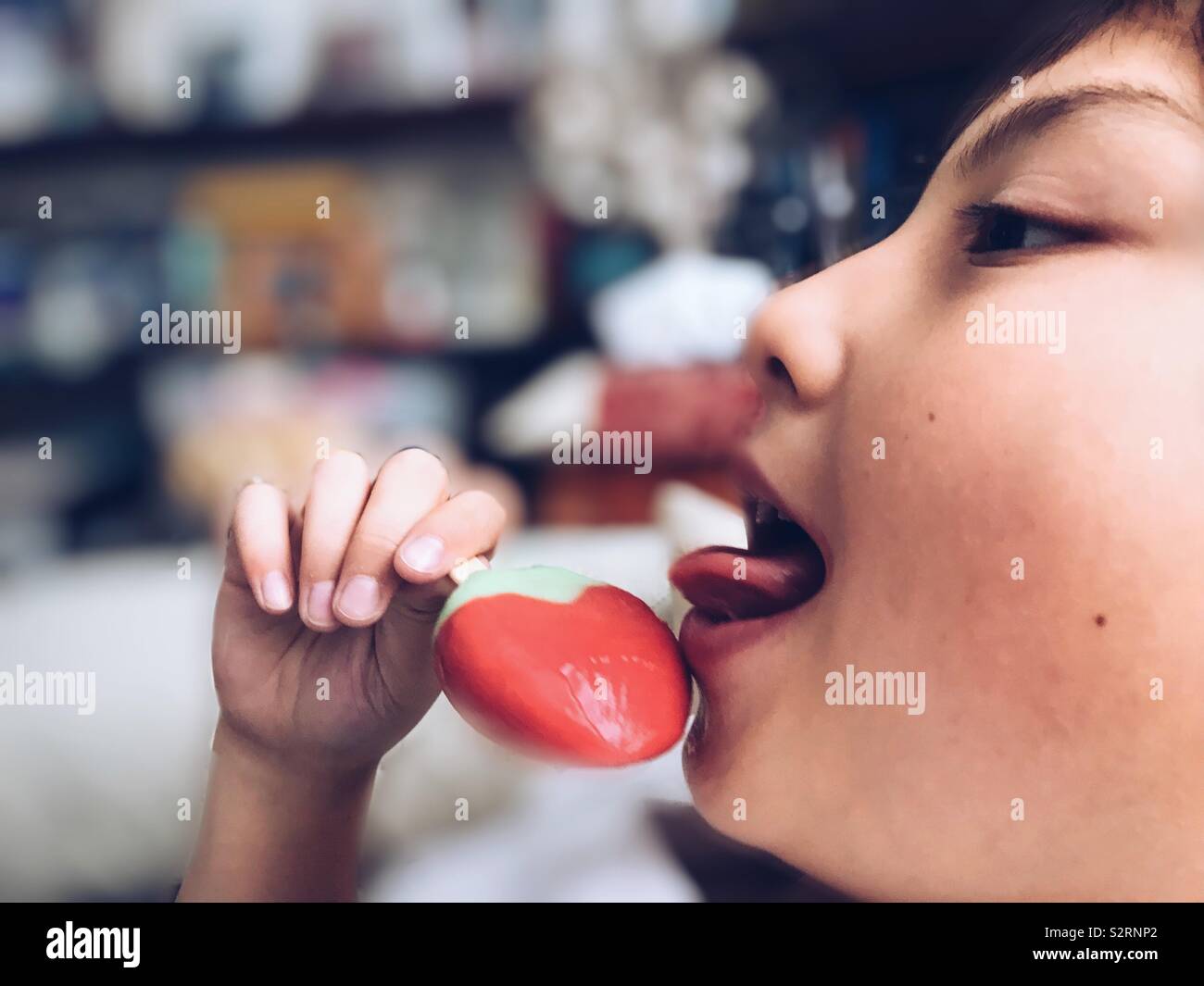 Ein Junge, der ein Strawberry flavoured Eis am Stiel. Stockfoto