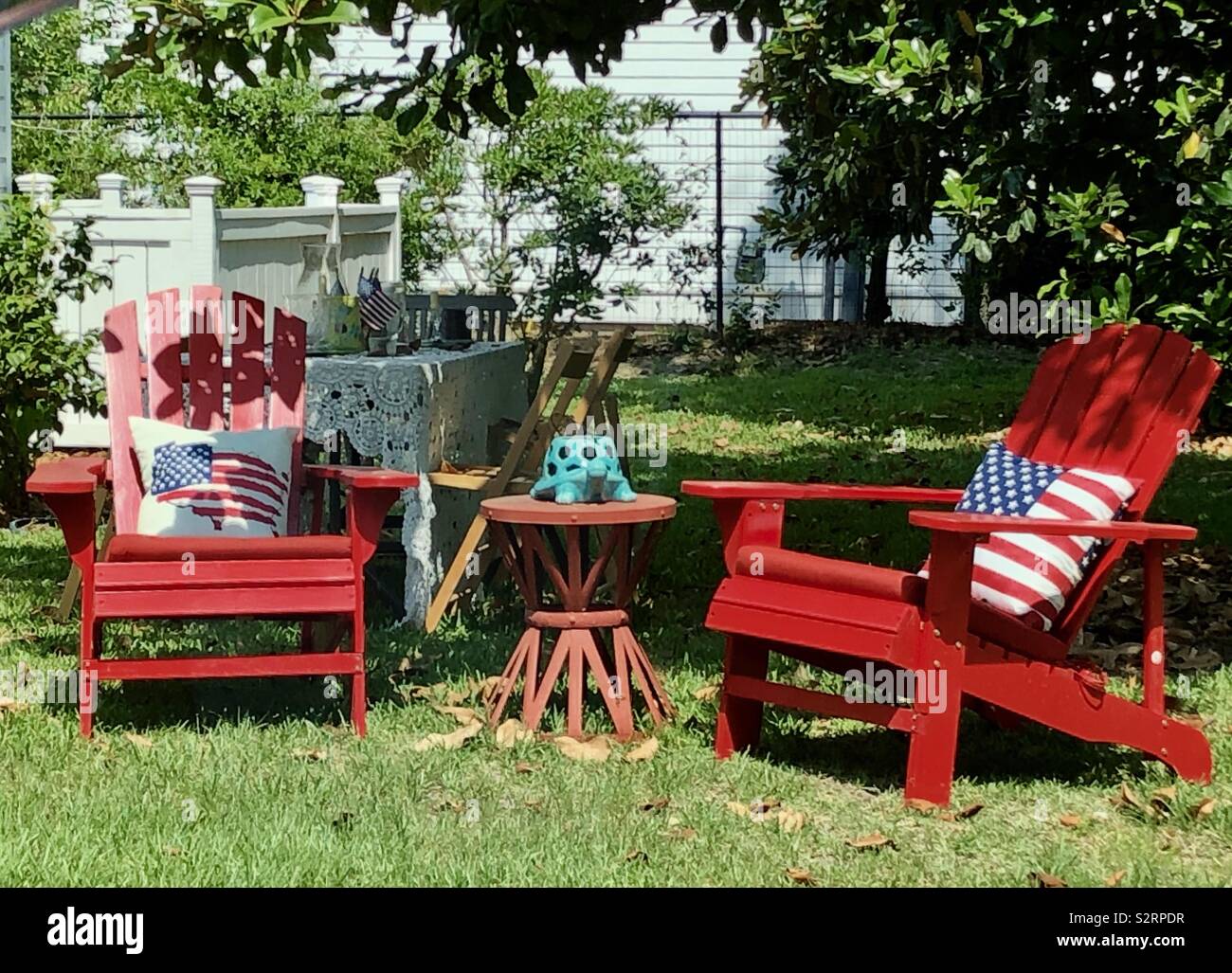 Zwei rote Adirondack Stühle auf Rasen mit amerikanischen Kissen Stockfoto