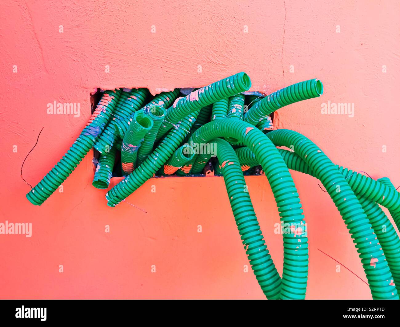 Gruppe von Wellpappe grün Kunststoff Rohre mit Putz und Farbe Flecken. Conduits für elektrische Kabel und Glasfaser. Bauarbeiten im Gange. Strom und schnelle Internetverbindung. - Smartphone-aufgenommenes Stockfoto