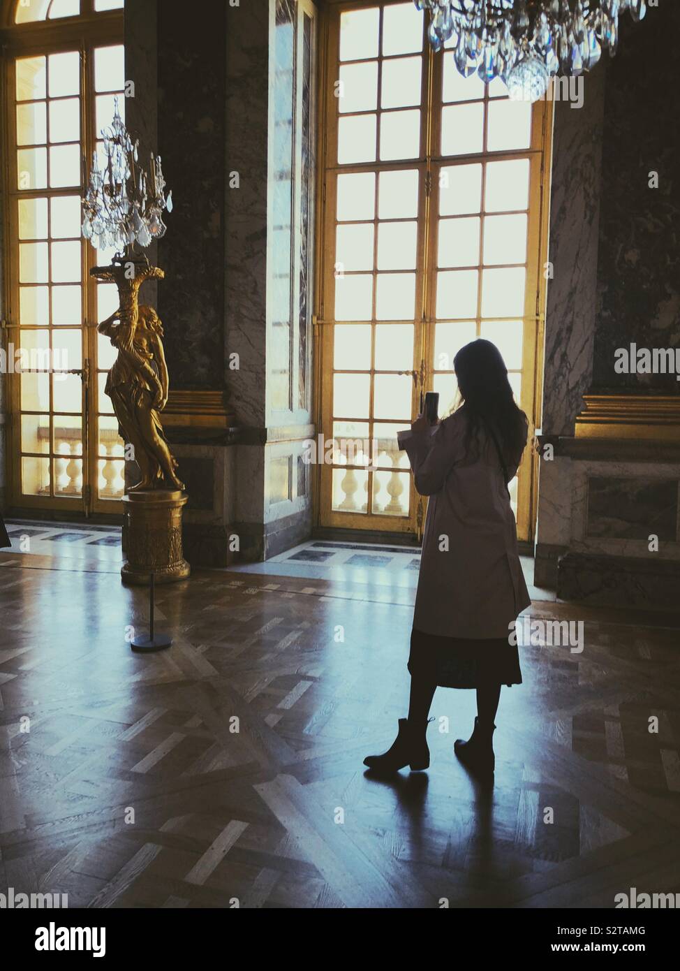 Junge Frau mit Foto auf Ihrem Telefon im Spiegelsaal in Versailles Stockfoto