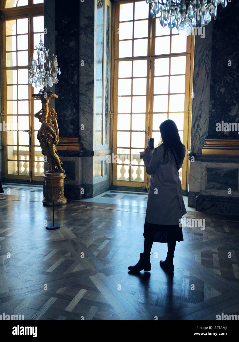 Junge Frau mit Foto auf Ihrem Telefon im Spiegelsaal im Schloss von Versailles Stockfoto