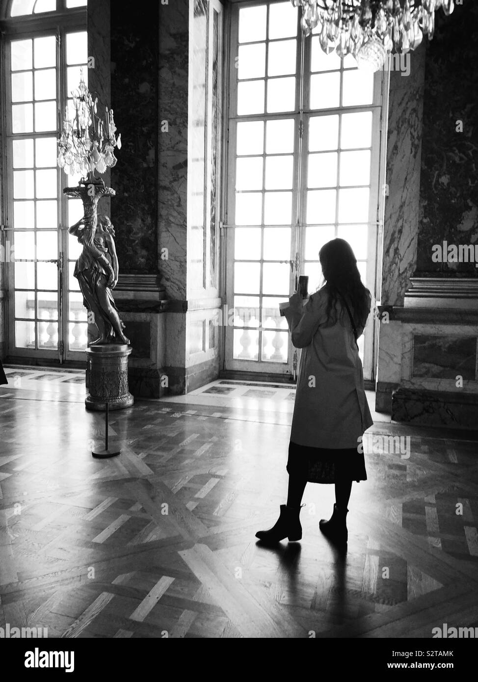 Junge Frau mit Foto auf Ihrem Telefon im Spiegelsaal im Schloss von Versailles Stockfoto