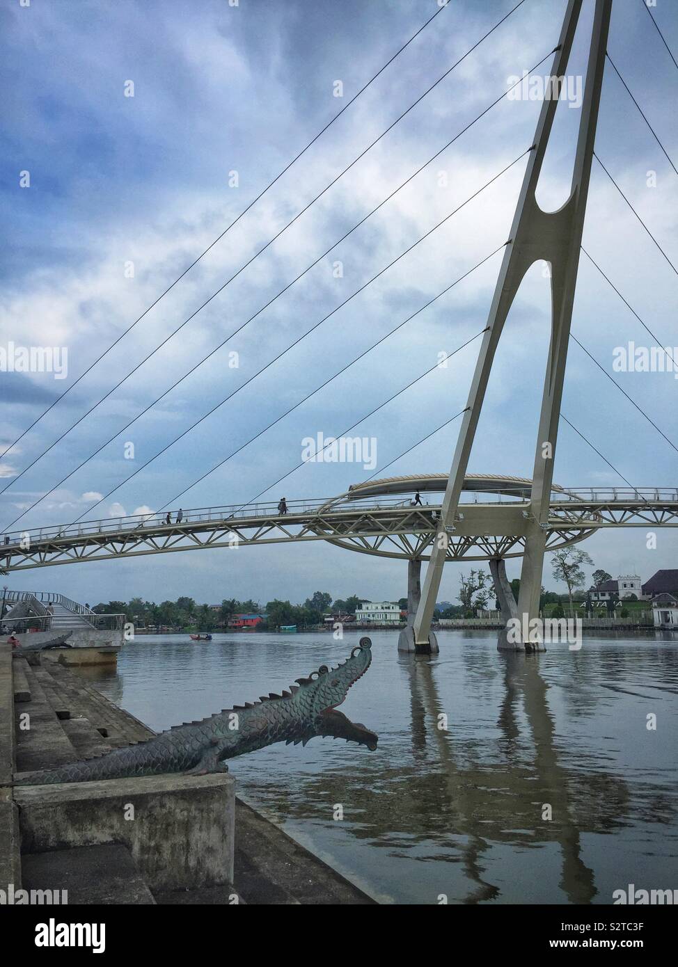 Einer der beiden Kanonen als Chinesische Drachen mit Blick auf den Fluss Sarawak gestaltet, mit der Darul Hana Brücke (Jambatan Darul Hana), Kuching, Sarawak, Malaysia Stockfoto