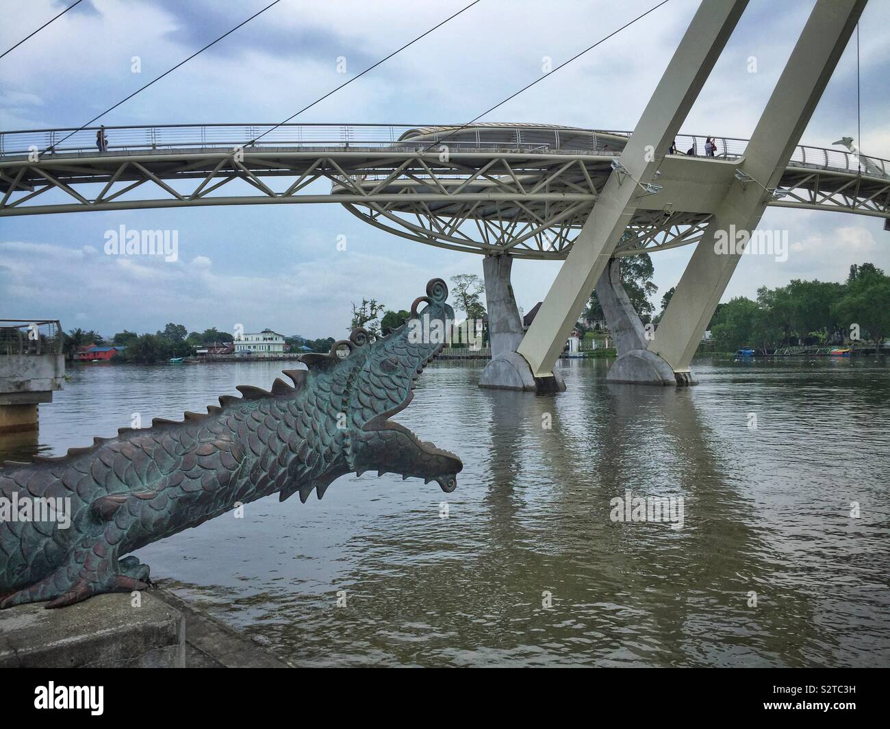Einer der beiden Kanonen als Chinesische Drachen mit Blick auf den Fluss Sarawak gestaltet, mit der Darul Hana Brücke (Jambatan Darul Hana), Kuching, Sarawak, Malaysia Stockfoto