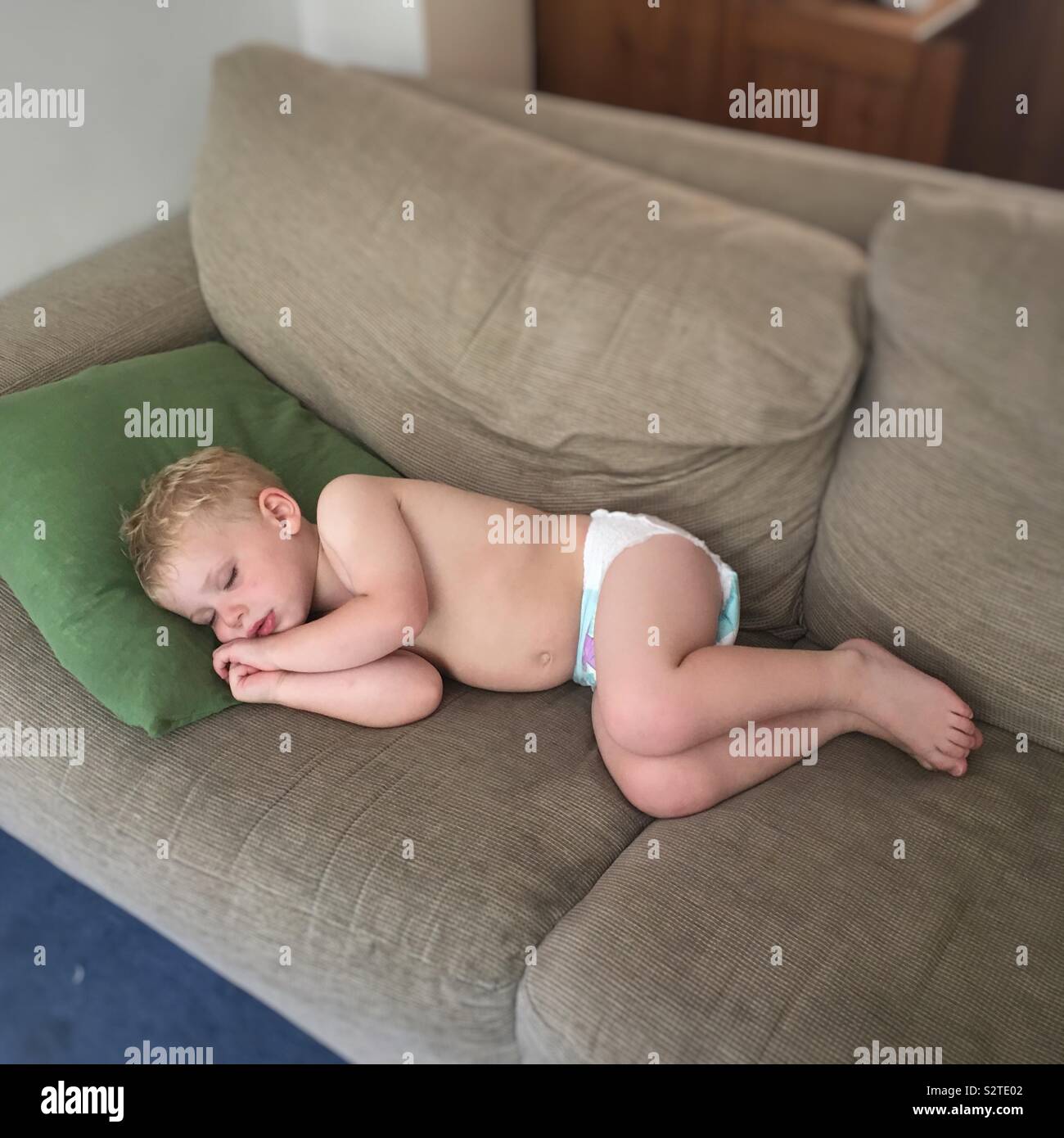 Zwei Jahre alten Sohn schläft auf dem Sofa bei dem heißen Wetter. Hampshire, England, Vereinigtes Königreich. Stockfoto