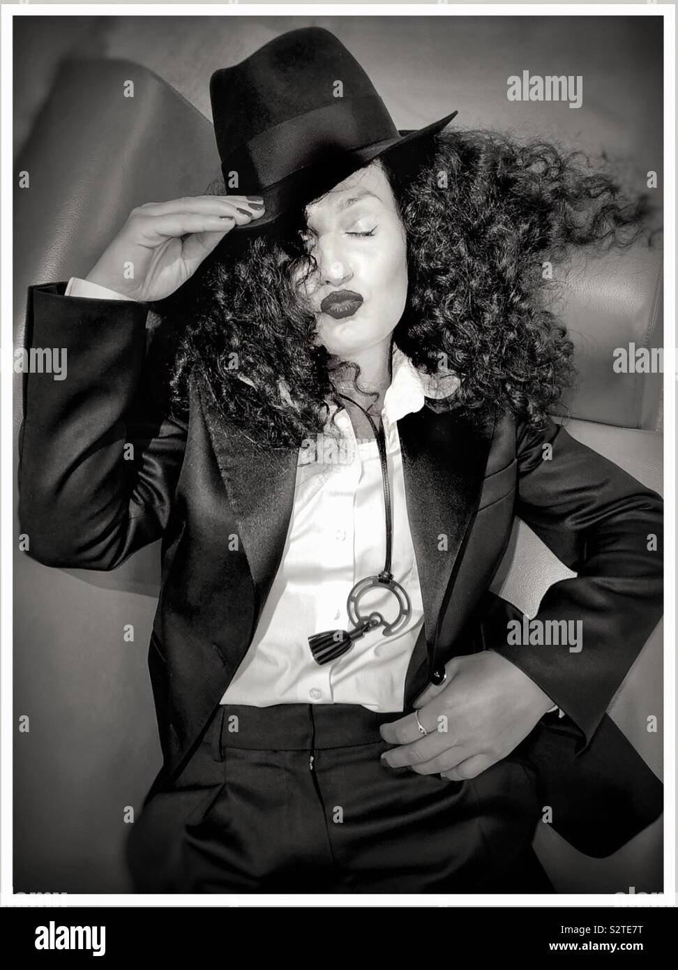 Eine Frau in einem Tuxedo bläst einen Kuss mit geschlossenen Augen. - Smartphone-aufgenommenes Stockfoto