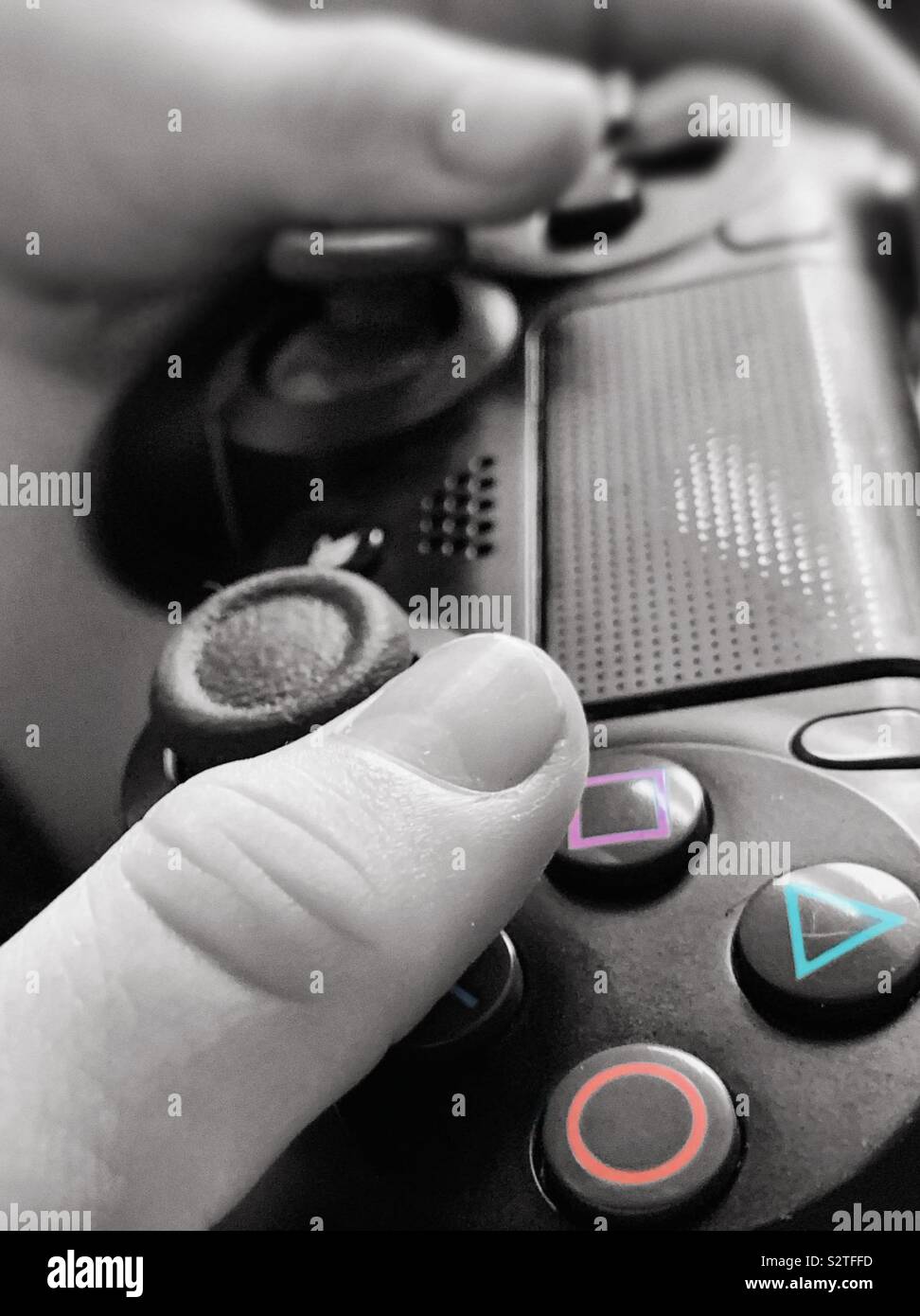 Child's Hand mit einem PlayStation PS4 Controller. Close up in Schwarz und Weiß mit Farben Stockfoto