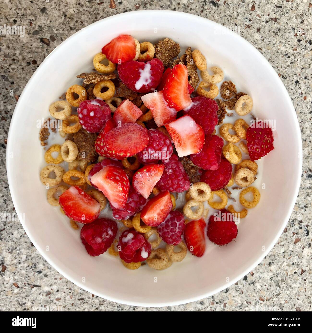 Nahaufnahme der Schüssel Müsli und Obst mit Milch von oben gesehen - Smartphone-aufgenommenes Stockfoto