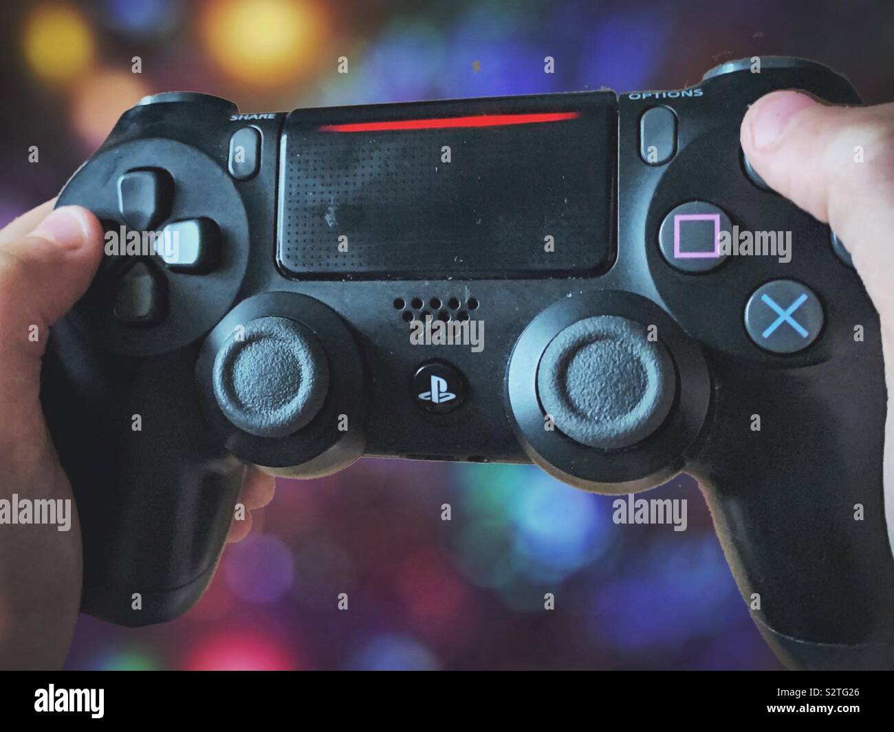 Hände halten ein PlayStation Controller. Gamer und Gaming - Smartphone-aufgenommenes Stockfoto