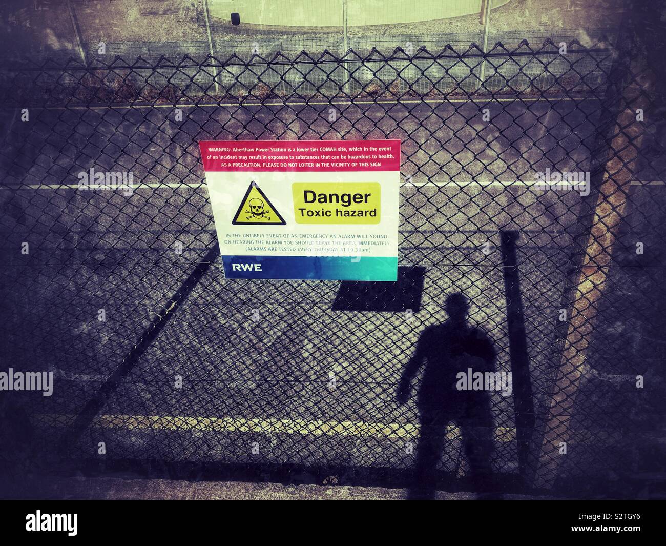 Gefahr Gefahr durch Gift Zeichen außerhalb eines Kraftwerks mit dem Schatten eines Menschen. Stockfoto