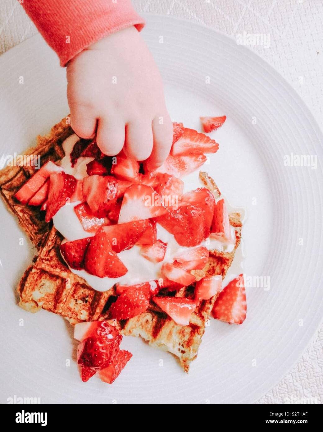 Die Hand des Kindes stehlen Frühstück Stockfoto