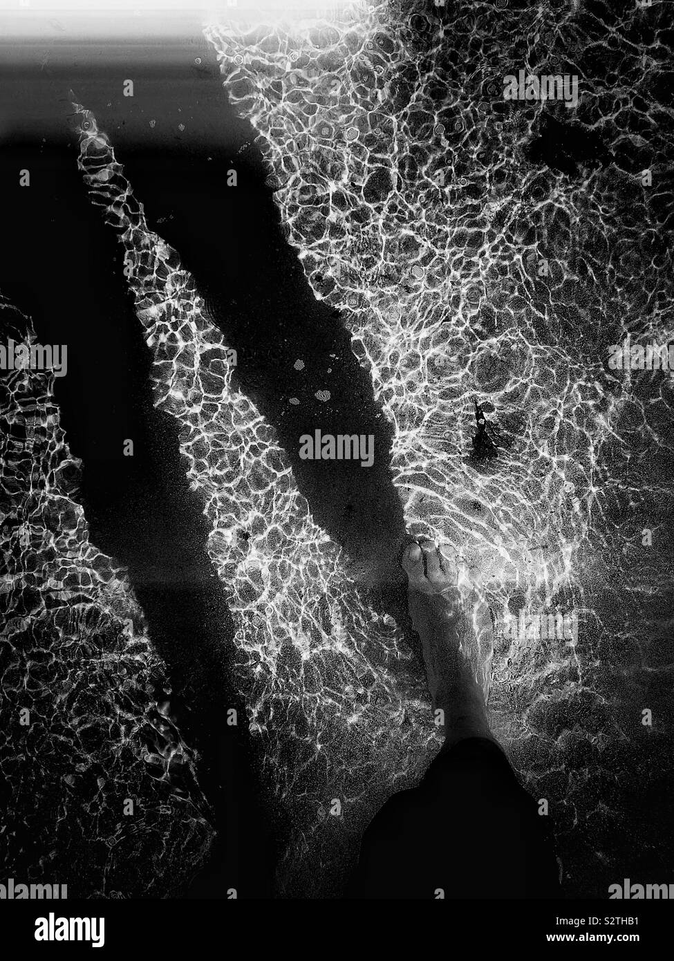 Starker Kontrast schwarz-weiß Bild der Schatten der Mann in klare sonnendurchflutete rippled Ozean - Smartphone-aufgenommenes Stockfoto