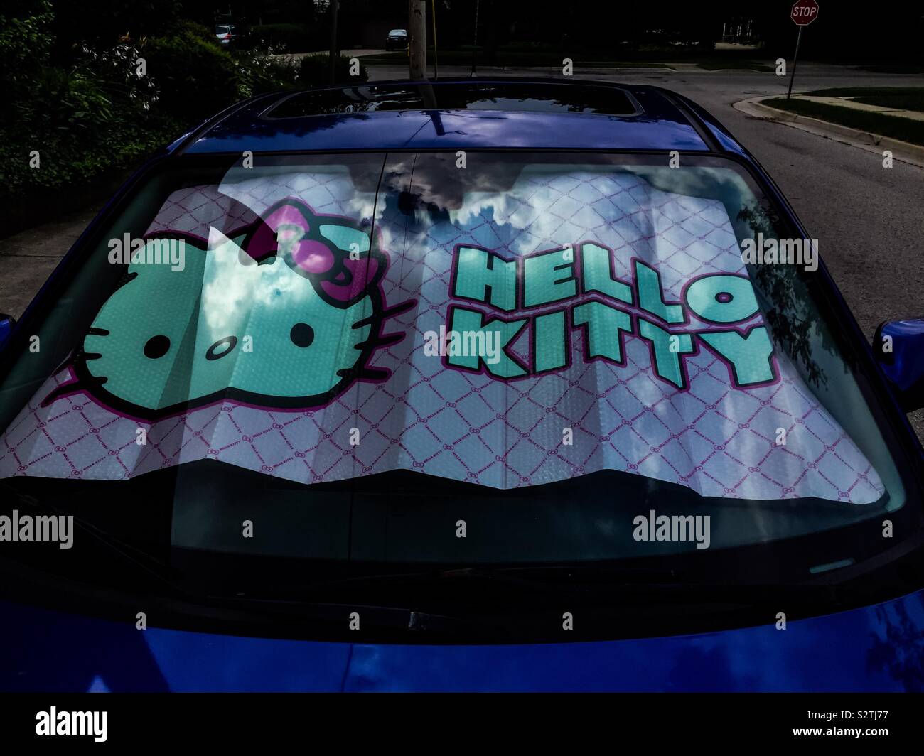 Hallo Kitty Windschutzscheibe an einem Auto. Wolken reflektiert. Blauer Himmel. Horizontal. Kopierbereich. Stockfoto