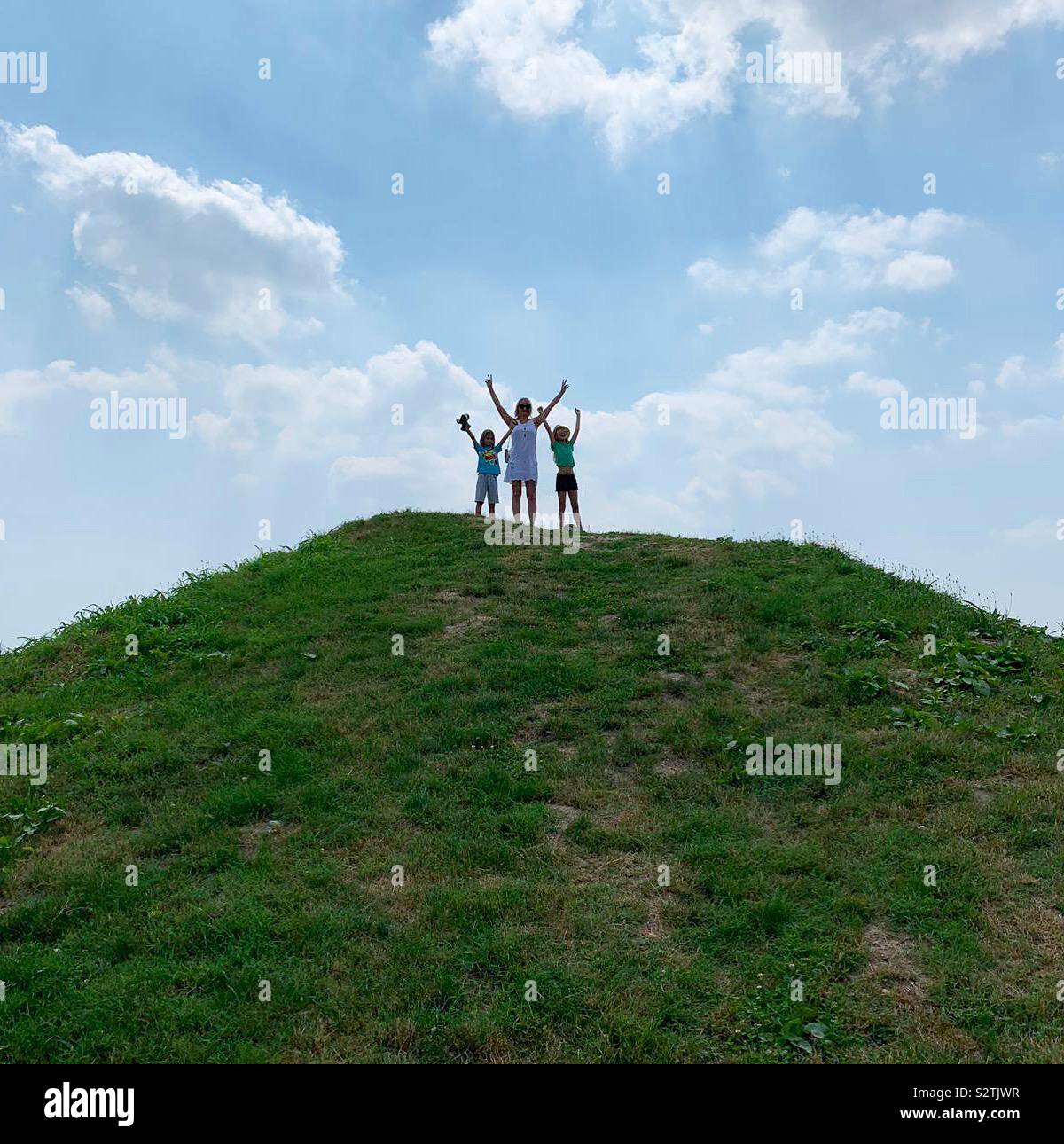 Mutter und Töchter mit Hände oben auf einem Hügel. - Smartphone-aufgenommenes Stockfoto