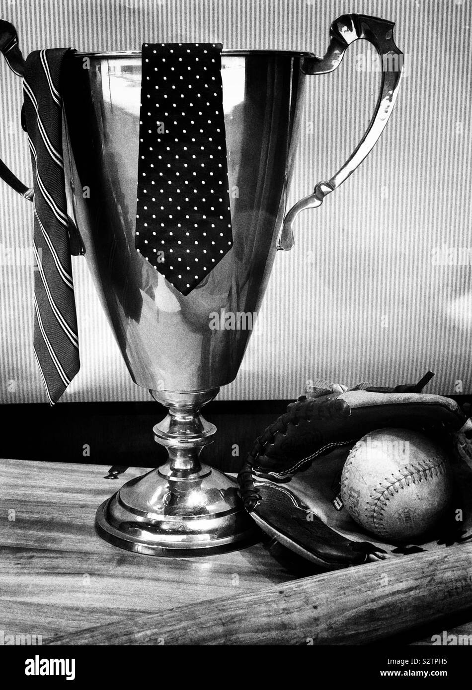 Eine Trophäe mit Krawatten auf es neben einem Softball Handschuh, Ball und Schläger in Schwarz und Weiß - Smartphone-aufgenommenes Stockfoto