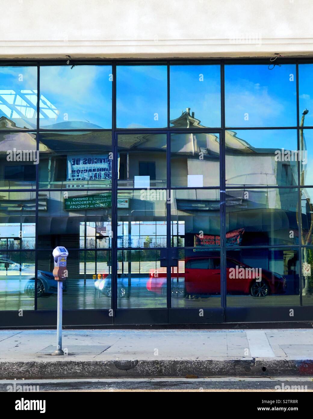 Eine Wand aus Glas reflektiert ein wild verzerrten Bild des Gebäudes auf der anderen Straßenseite. Stockfoto