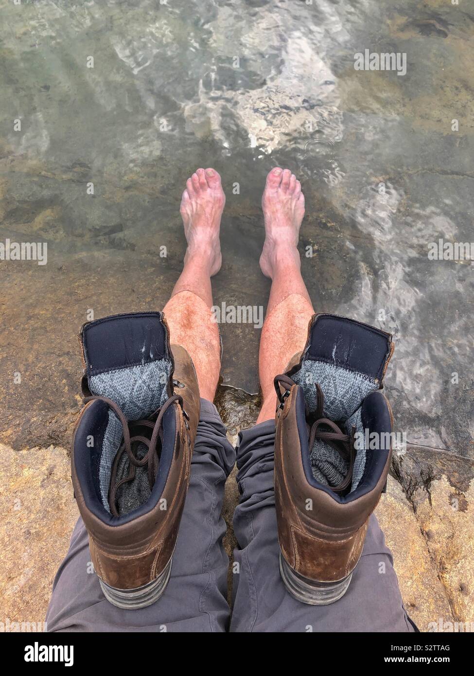 Abkühlen der Füße in einem Bergsee nach einem langen Spaziergang. Stockfoto