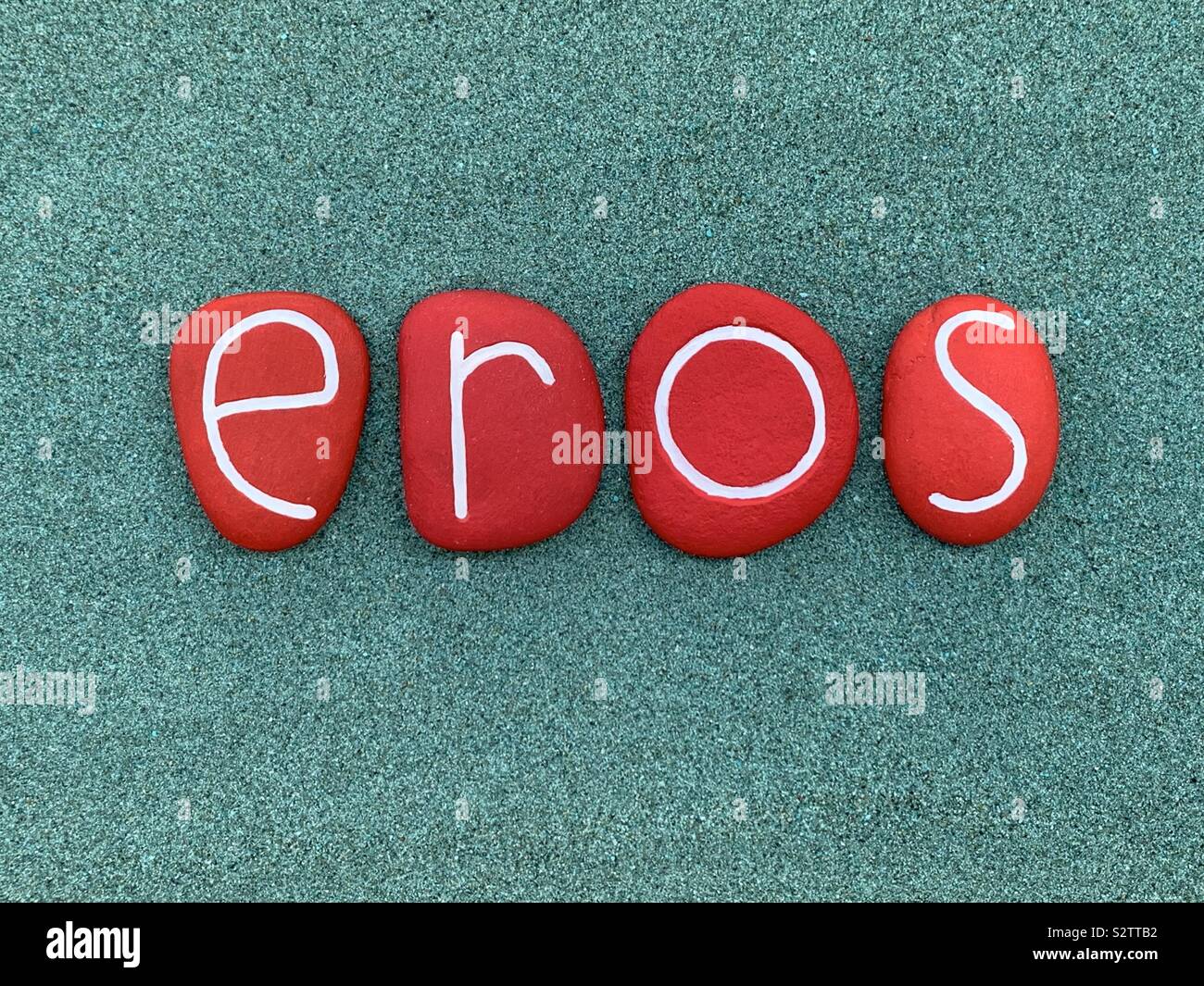 Eros, männliche Vornamen besteht aus rot gefärbten Stein Briefe über grünen Sand Stockfoto