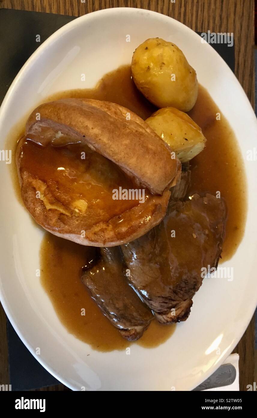 Sonntagsbraten - Rindfleisch Abendessen mit Yorkshire Pudding, Soße und Bratkartoffeln Stockfoto