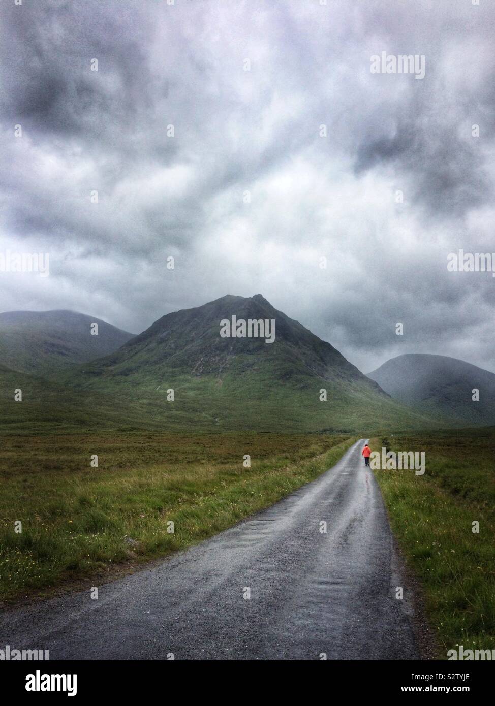 Mann zu Fuß auf eine leere roadat Glencoe, Schottland, Vereinigtes Königreich - Smartphone-aufgenommenes Stockfoto