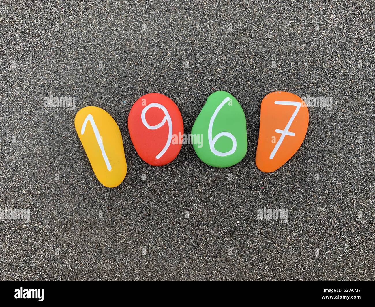 1967 Jahr komponiert mit bunten Steine über schwarzen vulkanischen Sand - Smartphone-aufgenommenes Stockfoto