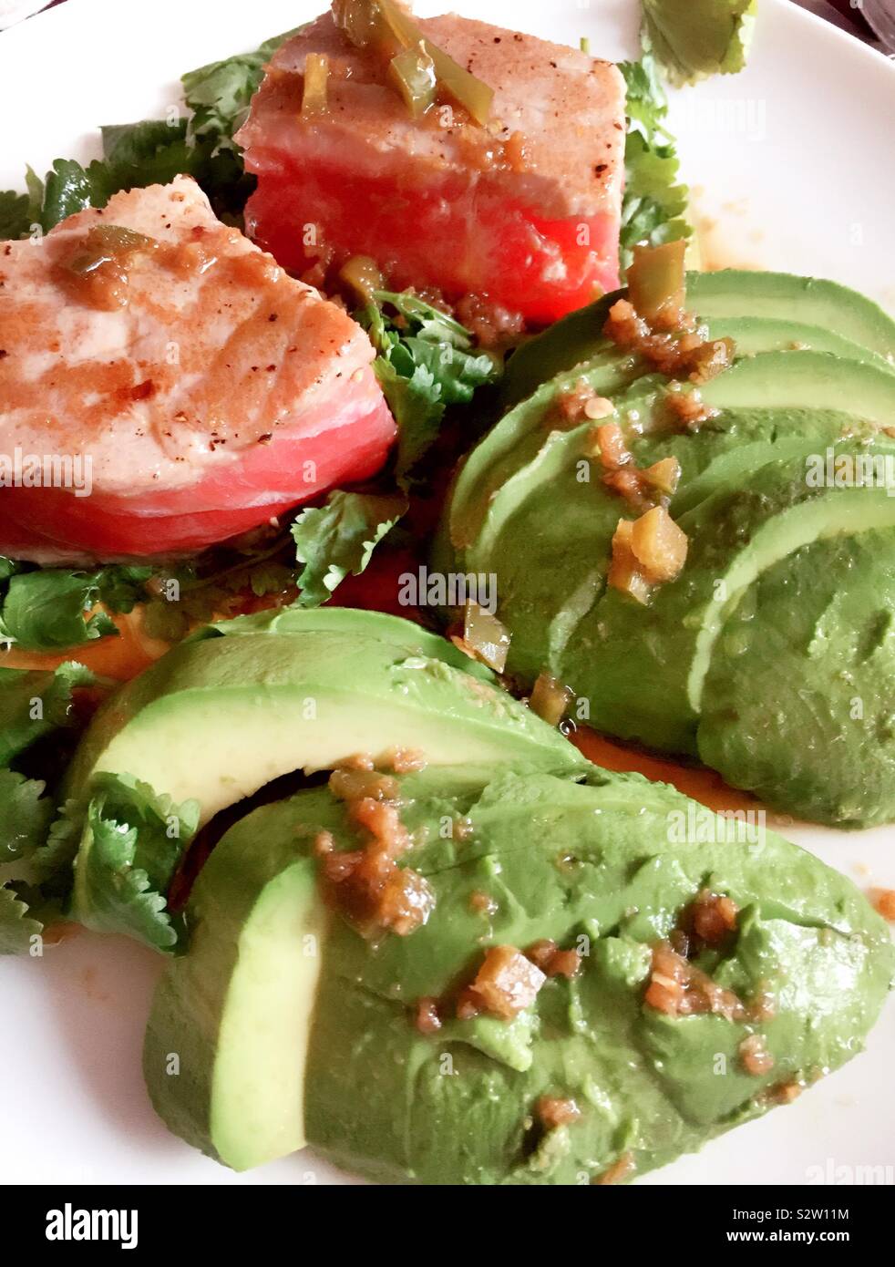 Gourmet entrée von gebratener Ahi-Thunfisch Thunfisch Filet auf einem Bett von Koriander und Avocados Stockfoto