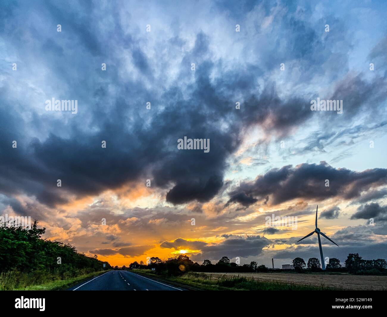 Dramatische Himmel bei Sonnenuntergang im Sommer während der Fahrt auf der Landstraße in Großbritannien Stockfoto