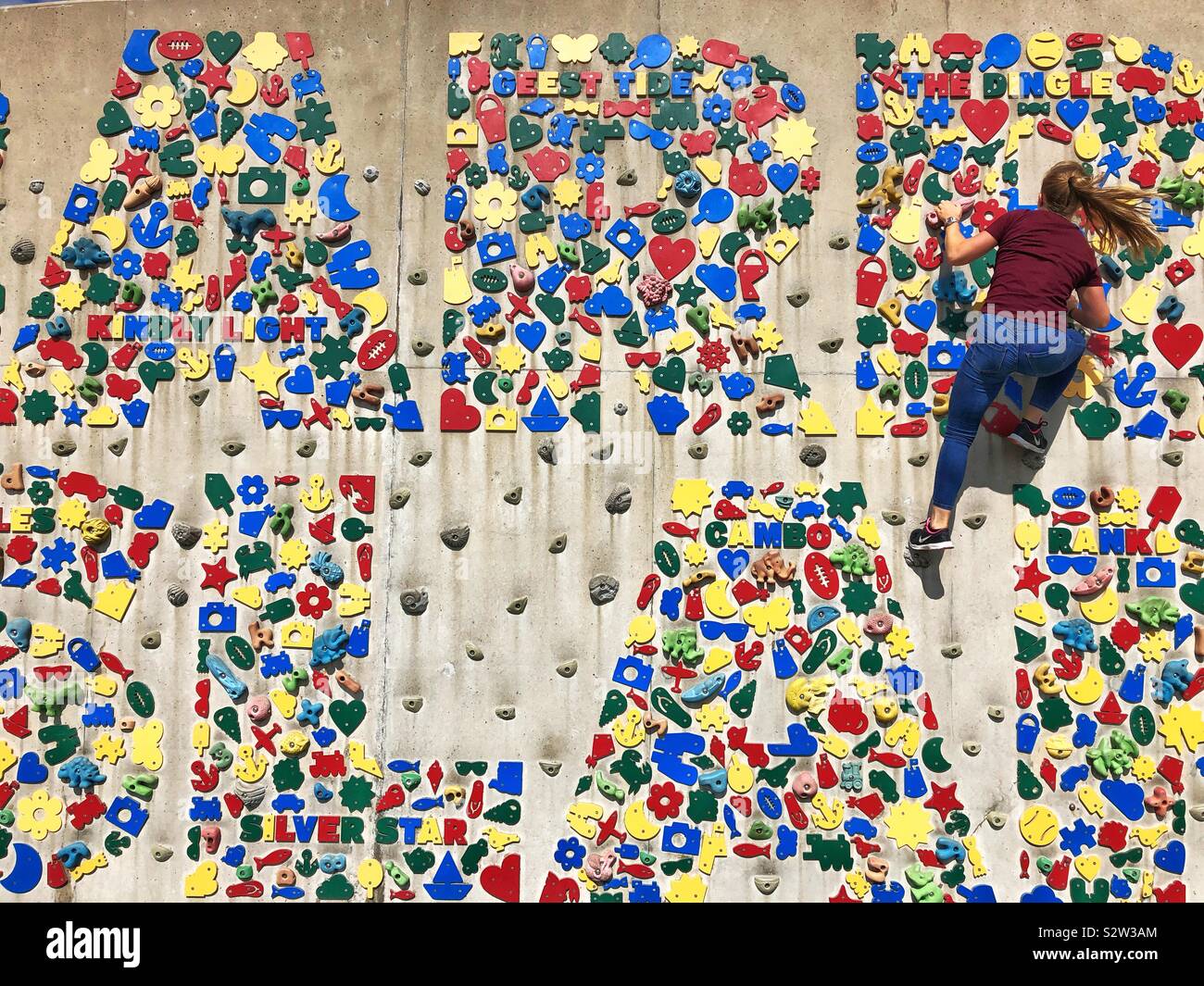 Junge Frau, Klettern an der Kletterwand bei Barry Island, South Wales, August. - Smartphone-aufgenommenes Stockfoto
