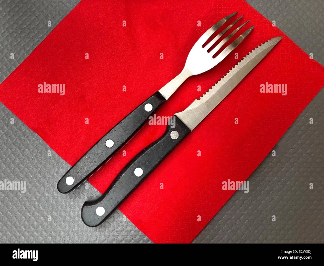 Messer und Gabel auf roter Serviette Stockfoto