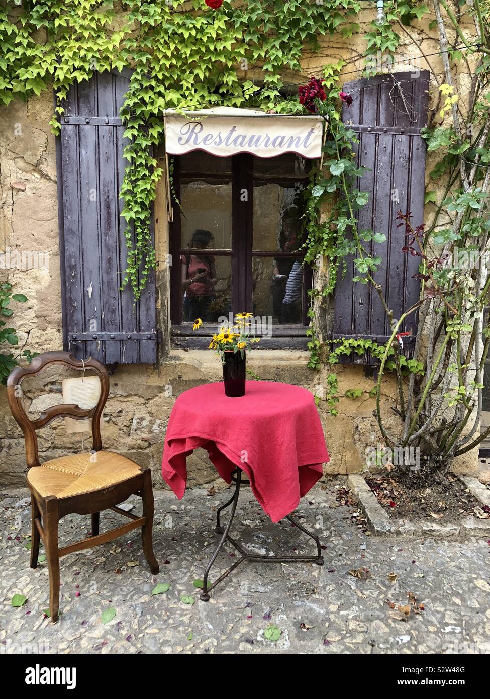 Tisch und Stuhl auf der Straße vor einem verlassenen Restaurant in Frankreich - Smartphone-aufgenommenes Stockfoto