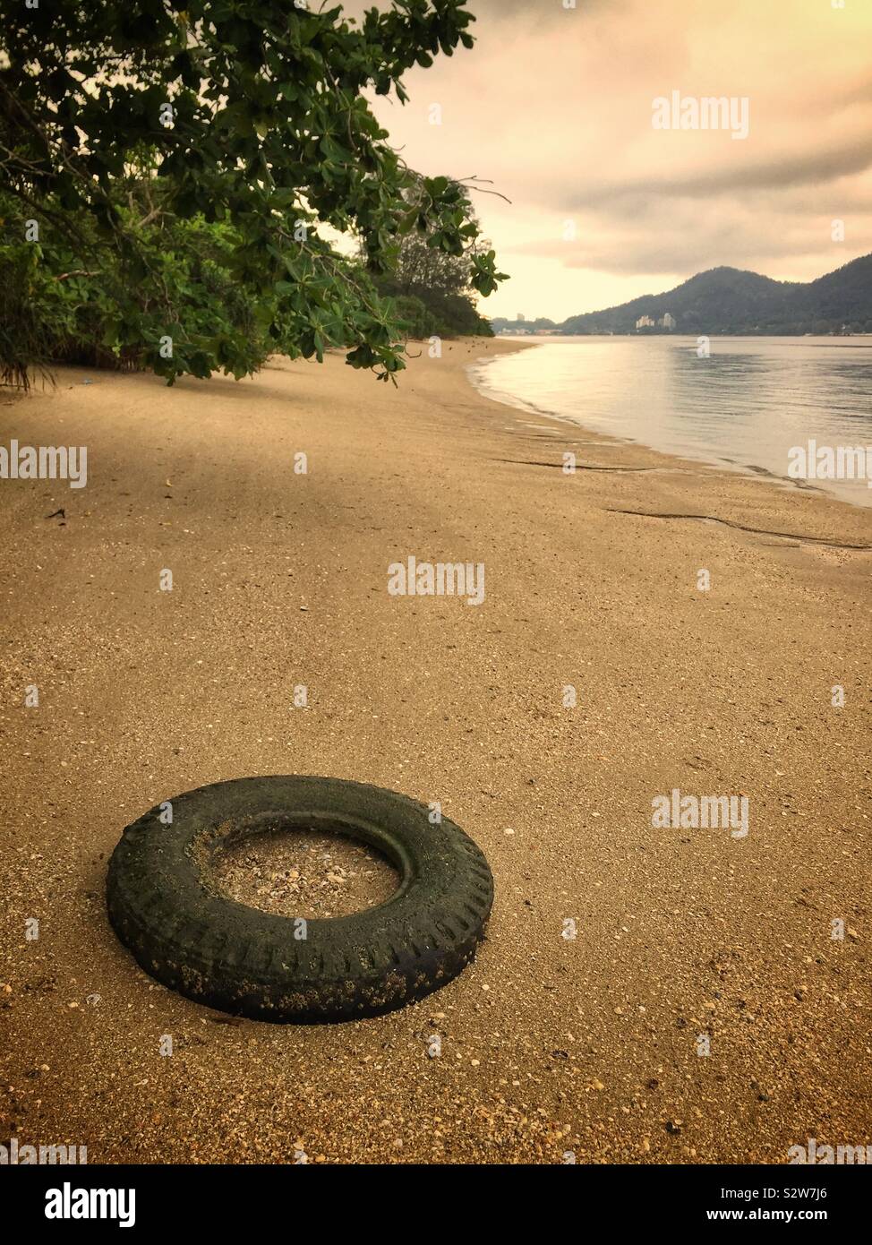 Ein Reifen halb als Verankerungspunkt für Boote am Strand begraben, manjung Flussmündung, in der Nähe von Lumut, Perak, Malaysia - Smartphone-aufgenommenes Stockfoto