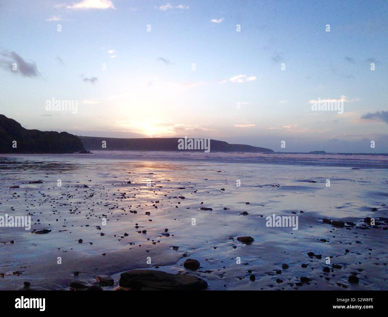 Pembrokeshire Strand mit Sonnenuntergang auf dem Wasser und Sand reflektieren Stockfoto