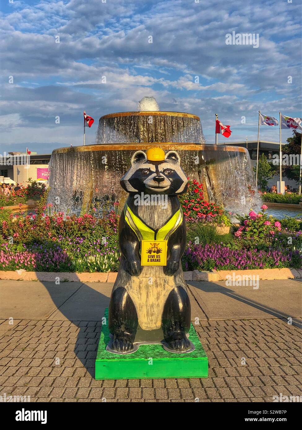 Eine gemalte Skulptur eines Waschbär stehend vor einem Brunnen. - Smartphone-aufgenommenes Stockfoto