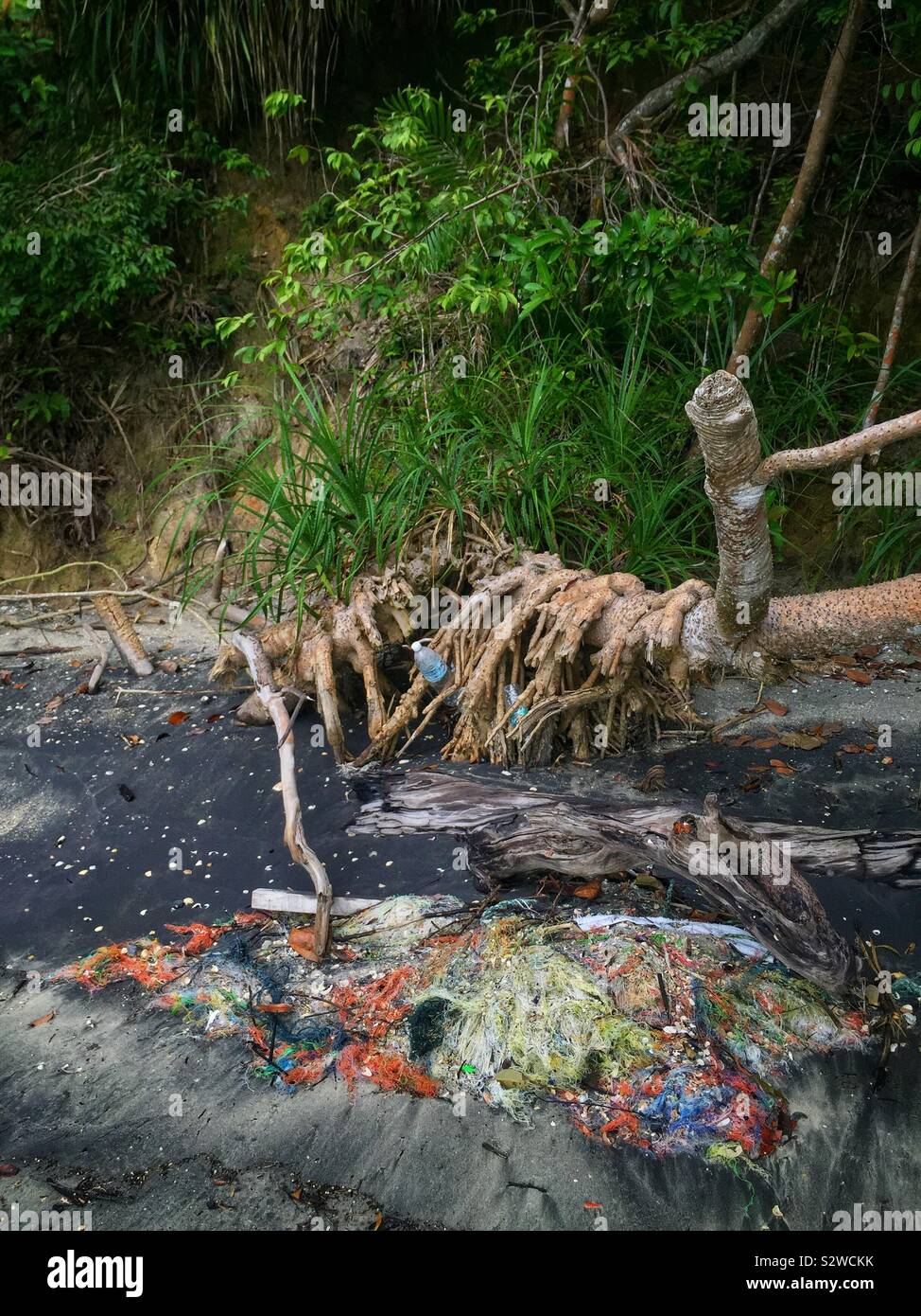 Ein Gewirr von Fischernetzen und Plastikflaschen gewaschen an Land am Strand mit Sand durch verschmutztes Grundwasser verfärbt, Straße von Malakka, in der Nähe von Lumut, Perak, Malaysia Stockfoto