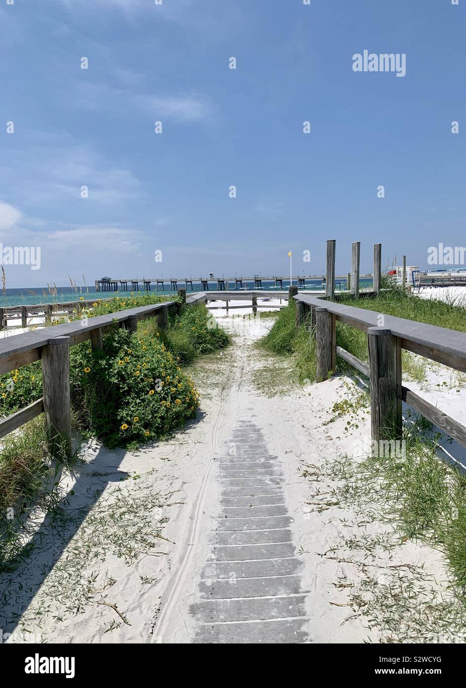 Fußweg zum Strand mit weissem Sand, die zu Fuß und Blick auf das Wasser und die entfernten Pier Stockfoto