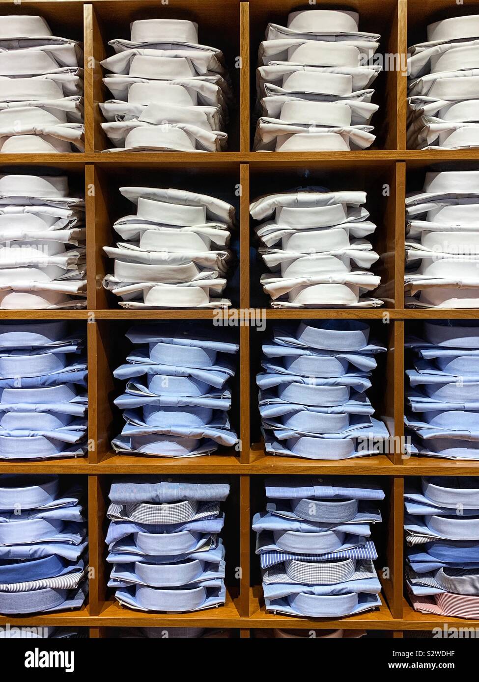 Stapel von Blue gefaltet und weißen collared Arbeit Hemden auf Holz Regale. Stockfoto