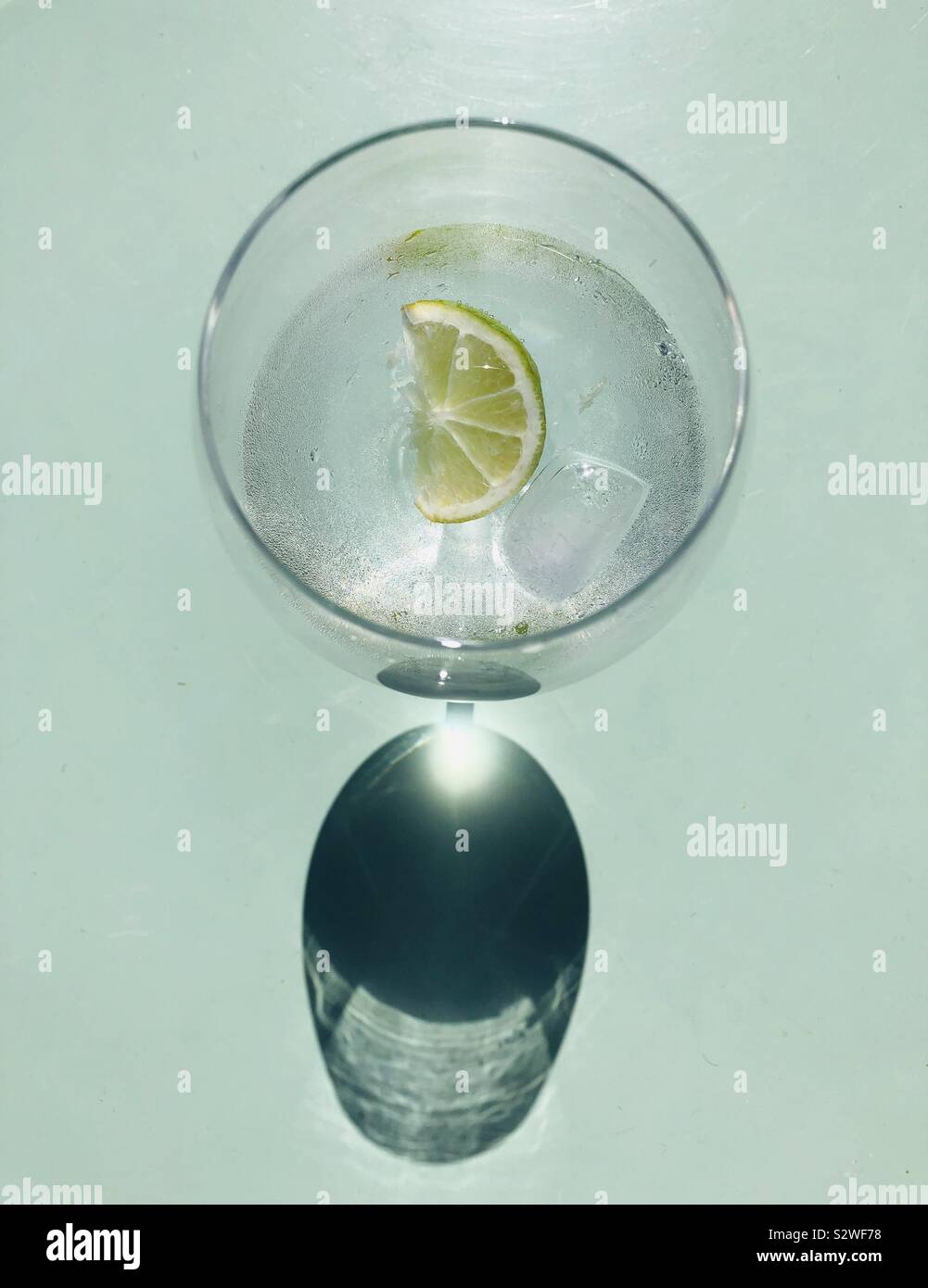 Gin und Tonic cocktail serviert mit Eiswürfeln und Limette Stockfoto