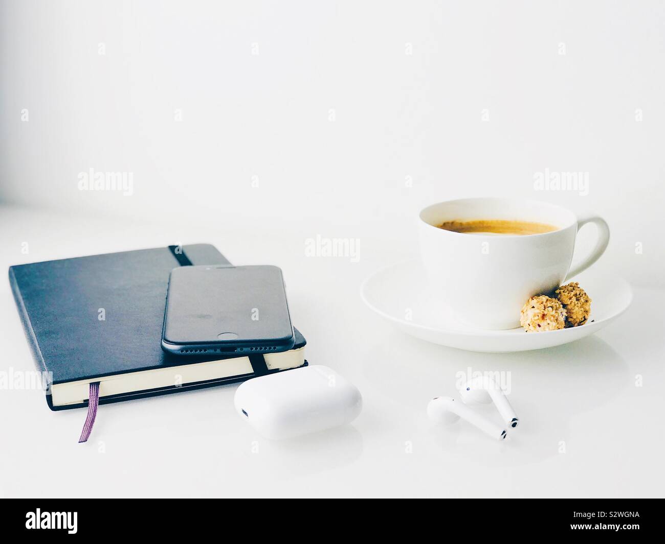 Notebook, Mobiltelefon, weiße Kopfhörer und Kaffee auf einem weißen Sideboard top Stockfoto