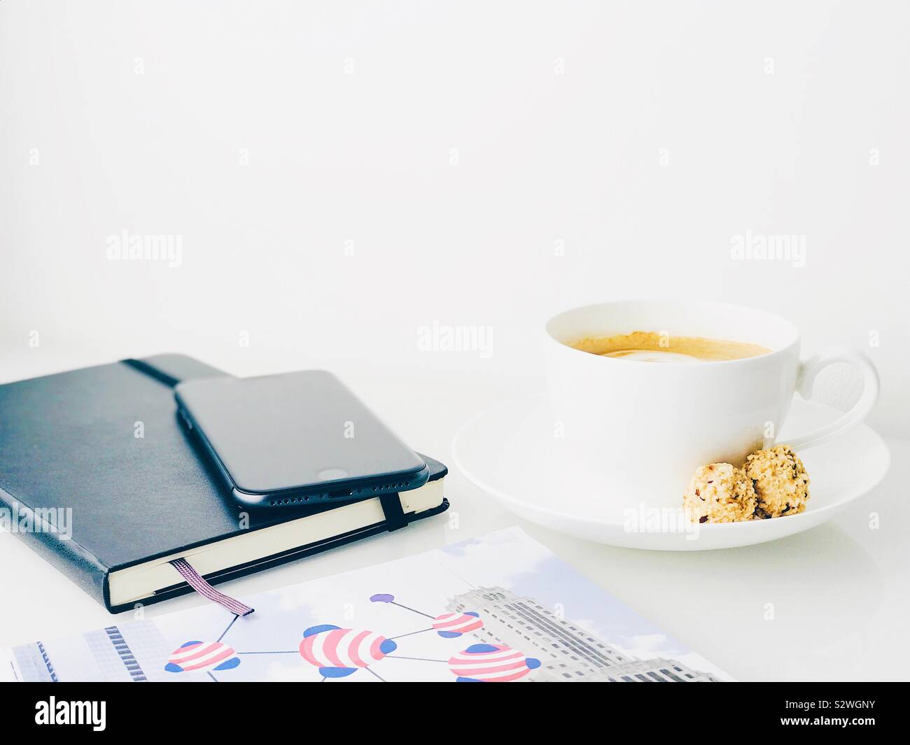 Notebook, Mobiltelefon, Kaffee und Magazin auf einem weißen oben auf einem Sideboard Stockfoto