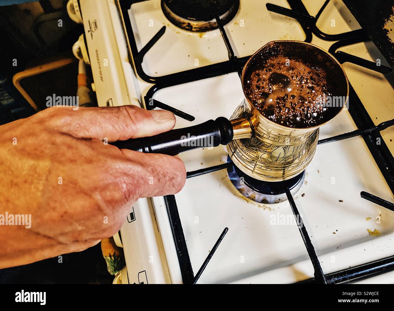 Mann, der Libanesischen Kaffee in traditionellen Messing Kaffeekanne. Namens rakweh auf Arabisch ist es enger an der Spitze, damit der Schaum oder achoueh zu bilden Stockfoto