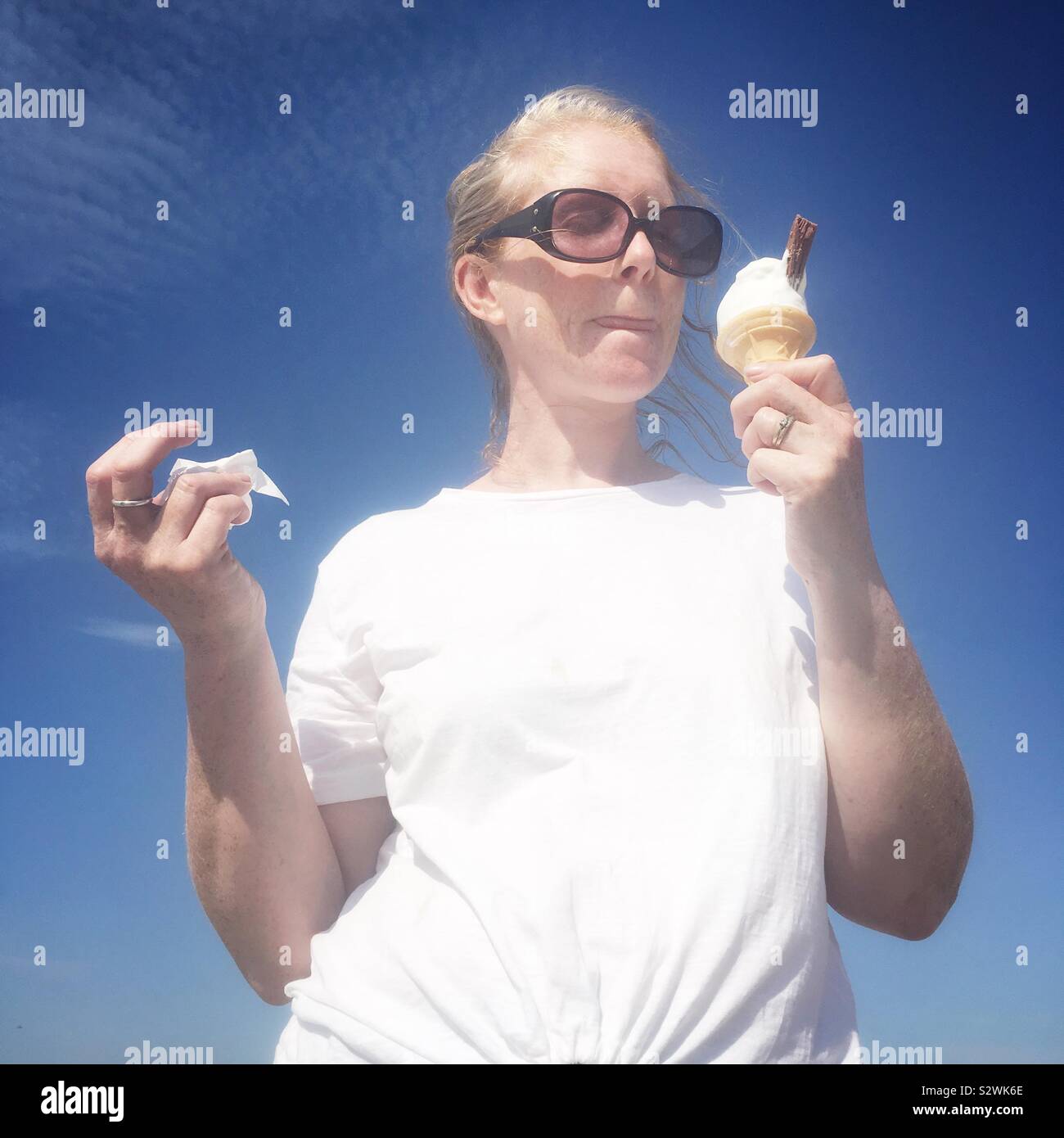 Frau In Sonnenbrille essen ein Eis. - Smartphone-aufgenommenes Stockfoto