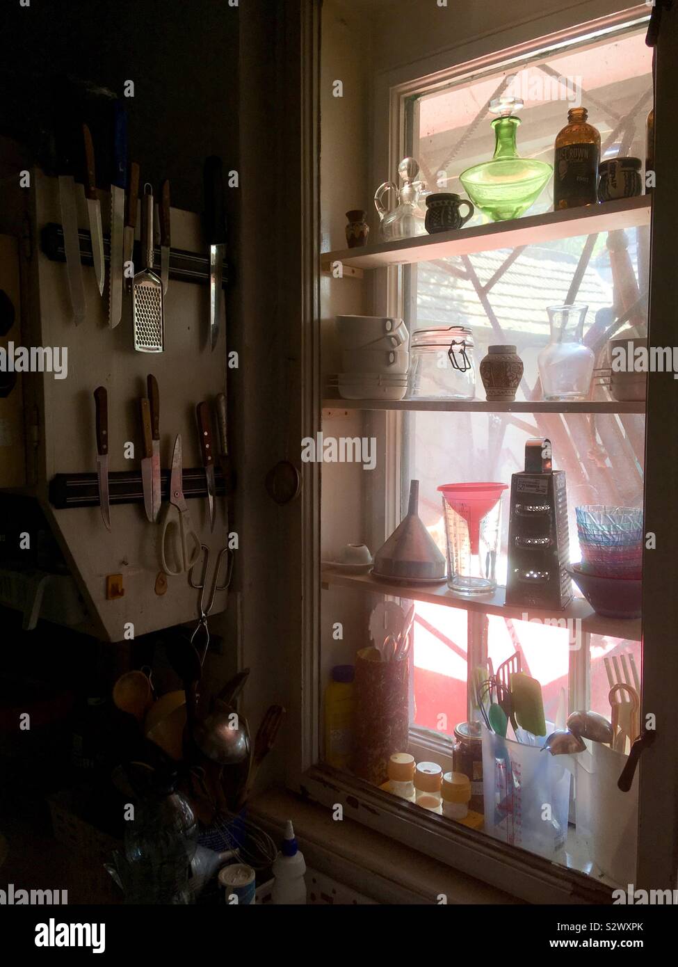 Retro Küche Fenster mit eingebauten Regalen und Schrank Seite voll von Besteck, Gläser, reibe, Trichter, Messer Stockfoto